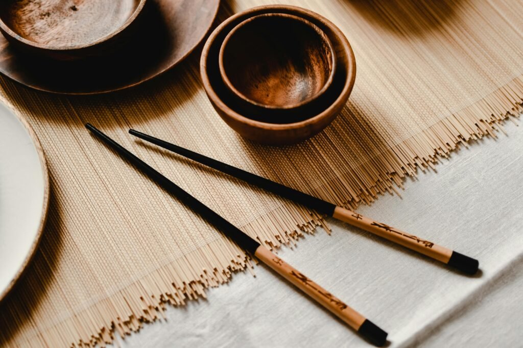 Aesthetic close-up of wooden bowls and chopsticks on a bamboo mat creating a minimalist dining setup.