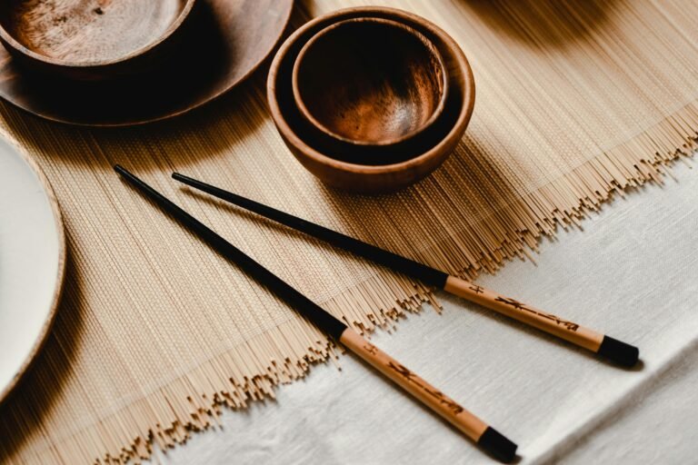 Aesthetic close-up of wooden bowls and chopsticks on a bamboo mat creating a minimalist dining setup.